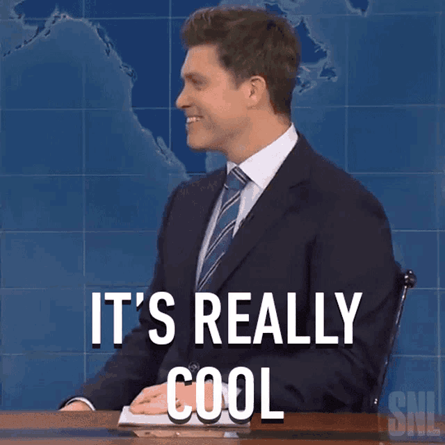a man in a suit and tie is sitting at a desk with the words " it 's really cool " above him