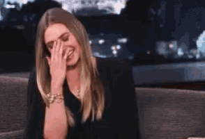 a woman covering her face with her hand while laughing .