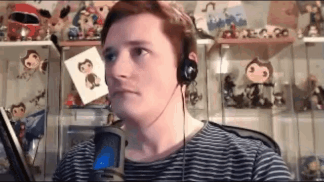 a man wearing headphones is sitting in front of a microphone in a room filled with toys .