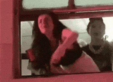 a woman is dancing in front of a window while another woman looks on .