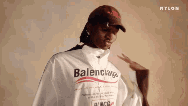 a person wearing a white balenciaga shirt and a hat