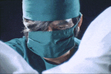 a close up of a surgeon wearing a mask and a hat
