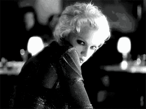 a black and white photo of a blonde woman in a black dress