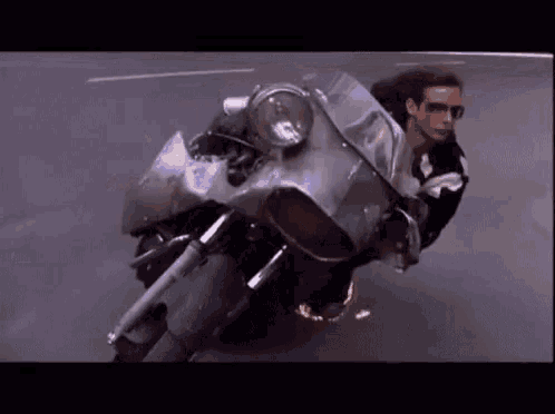 a man is riding a motorcycle down a street with a large windshield .