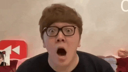 a man with glasses is making a surprised face .
