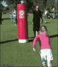 a little girl is running towards a punching bag that says r ent.
