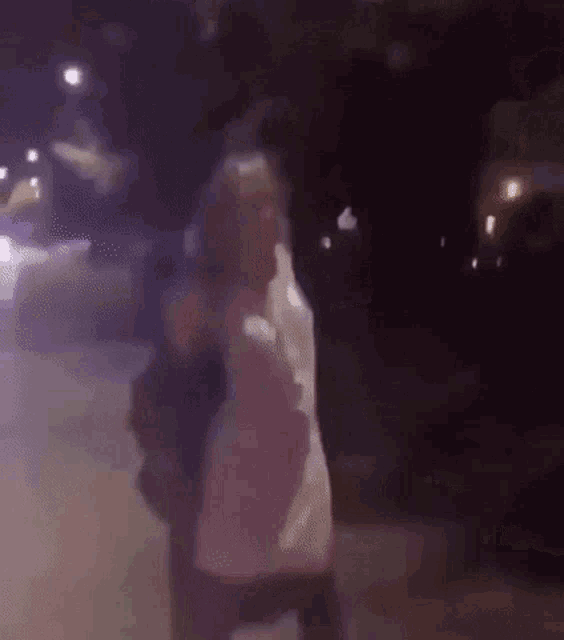 a woman in a white dress is dancing on a street at night .
