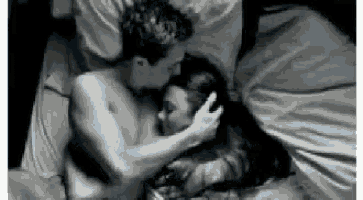 a man and a woman are kissing on a bed .