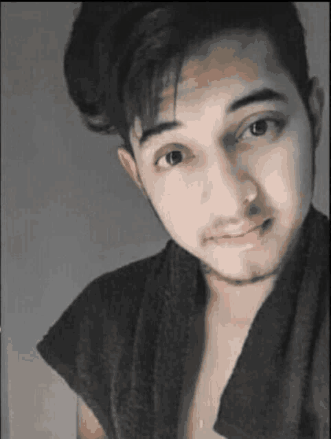 a young man with a beard and a towel around his neck is smiling for the camera .