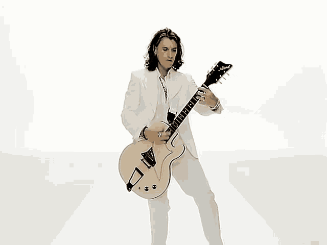a man in a white suit playing a guitar