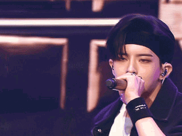 a man wearing a beret is singing into a microphone while wearing a wristband that says jpn on it