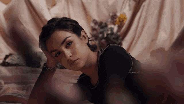 a woman in a black shirt is laying on a bed
