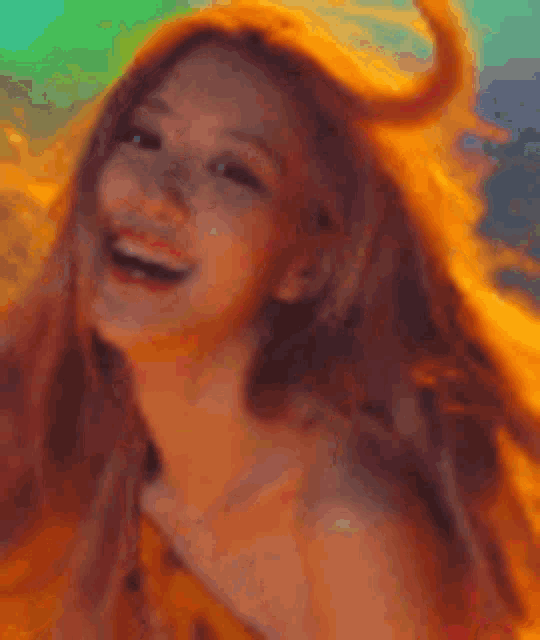 a close up of a woman 's face with her hair blowing in the wind and smiling .