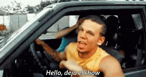 a man in a yellow tank top is driving a car and talking to someone .