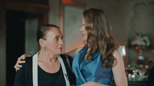 a woman in a blue dress is hugging an older woman