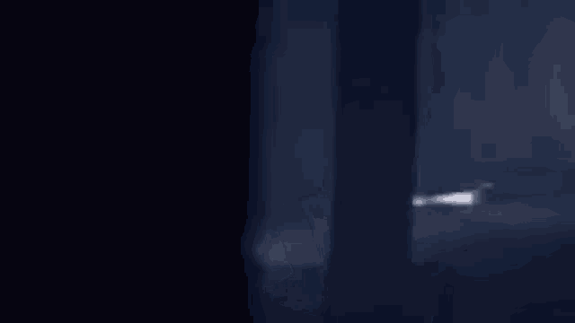 a blurry picture of a person walking in a dark room with a window .