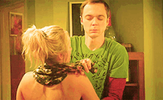 a man in a green shirt holds a woman 's shoulder