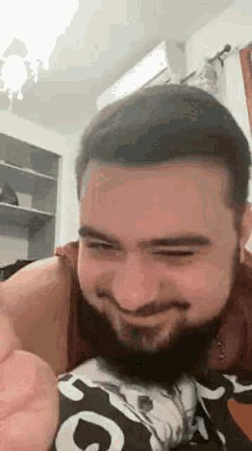 a man with a beard is making a funny face while laying in bed .