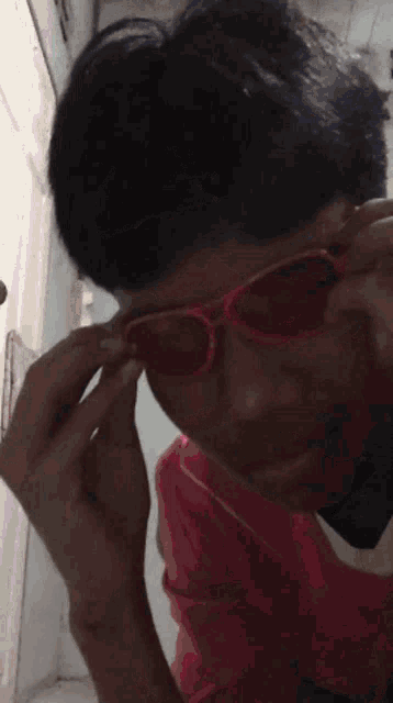 a young man wearing a pair of red sunglasses looks at the camera