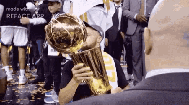 a man is kissing a basketball trophy while standing next to a man in a suit .