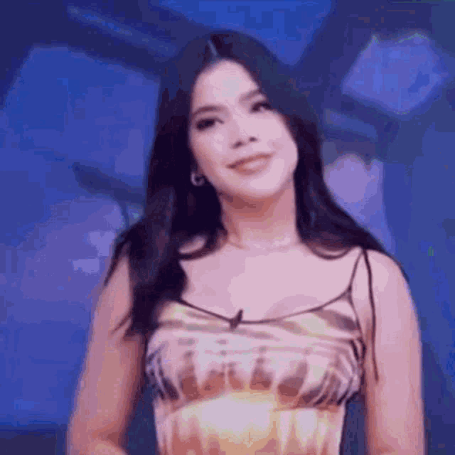a woman in a dress is standing in front of a blue background .