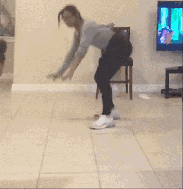 a woman is dancing on a tiled floor in a living room .