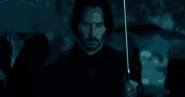 keanu reeves is holding an umbrella in the rain .