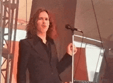 a man in a black suit is singing into a microphone .