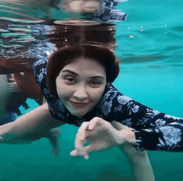 a woman is swimming underwater and smiling for the camera .
