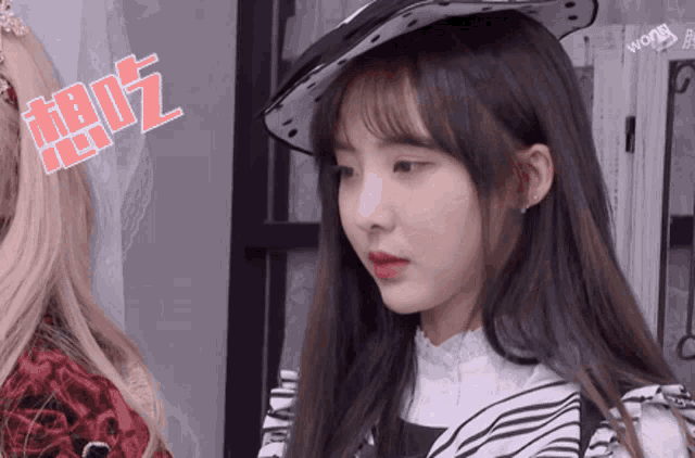 a girl wearing a hat with chinese writing on it looks at the camera