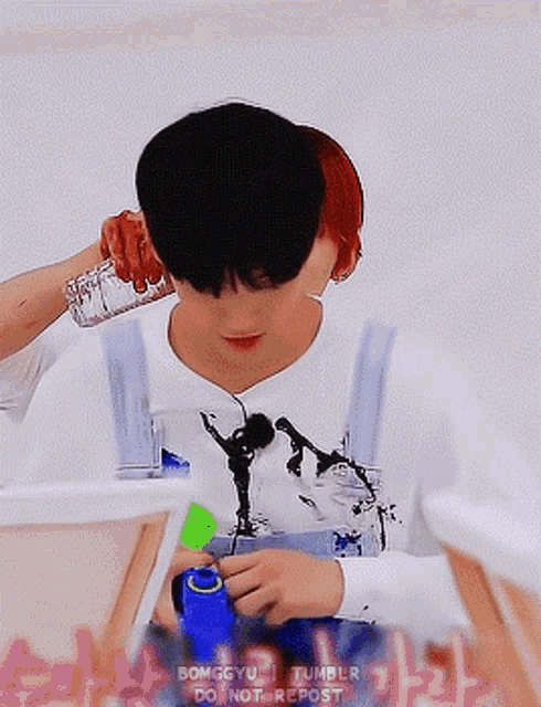 a boy is holding a bottle of water over his ear