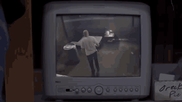 a tv screen shows a man dancing in a room next to a box that says " greek pie "