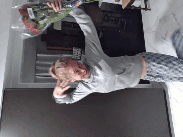 a woman in pajamas holds a bouquet of flowers in her hand