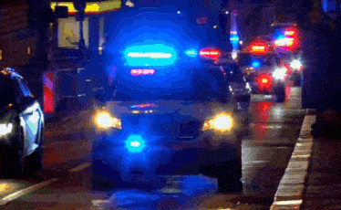 a police car is driving down a street at night with the lights on