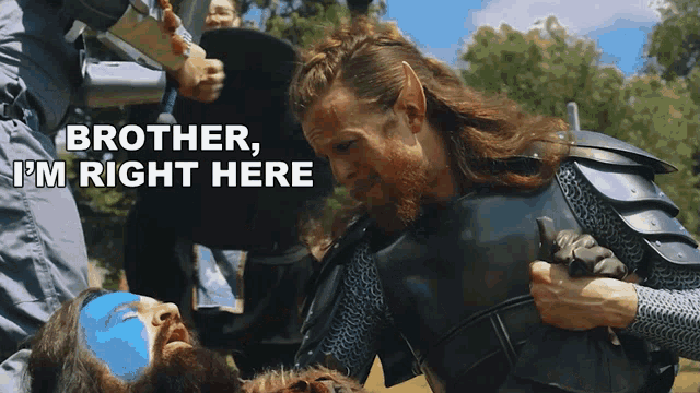 a man with a beard and blue paint on his face says " brother i 'm right here " while holding another man