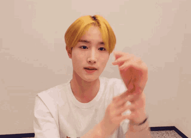 a young man with yellow hair is wearing a white shirt