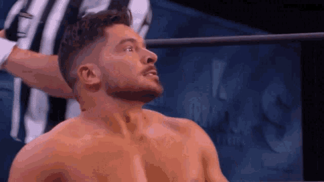 a man with a beard is standing in a wrestling ring without a shirt on .