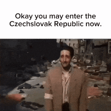 a man in a suit is standing in a destroyed city and talking to someone .