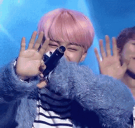 a girl with pink hair is holding a microphone in front of her face