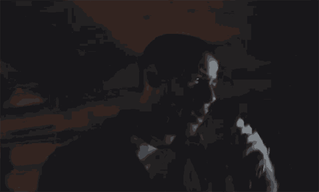 a man in a suit is smoking a cigarette in the dark .