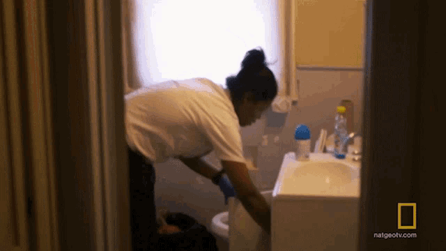 a woman cleaning a bathroom with natgeotv.com written on the corner