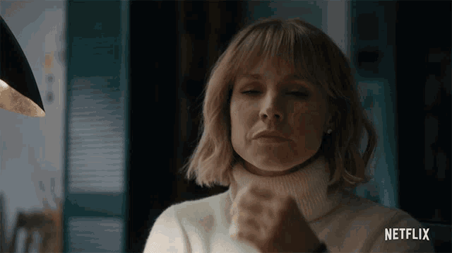 a woman in a white turtleneck sweater with a netflix logo behind her