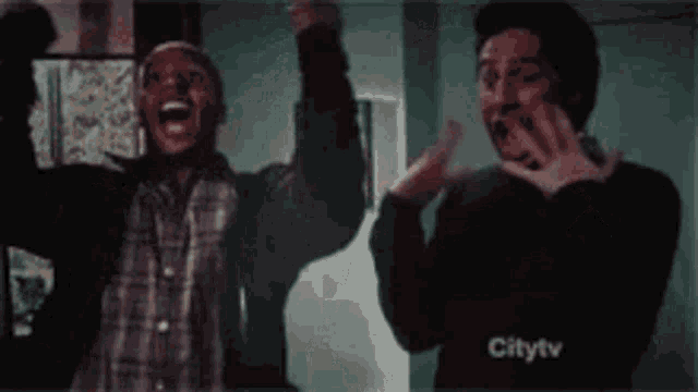 two men are standing next to each other with their hands in the air .