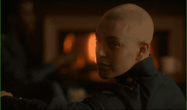 a man with a shaved head in front of a fire