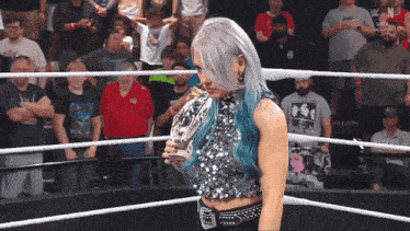 a woman holding a trophy in a wrestling ring with the letters w on the bottom