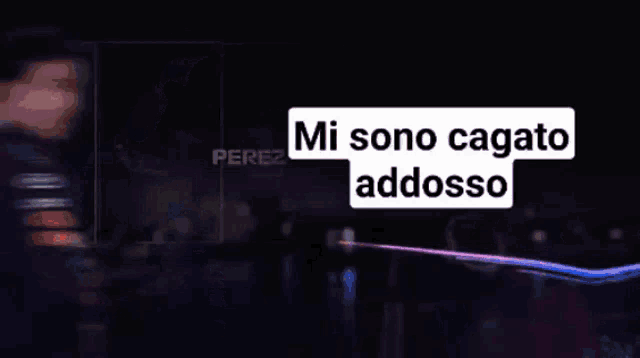 a man wearing a red bull jacket stands in front of a sign that says " mi sono cagato addosso "