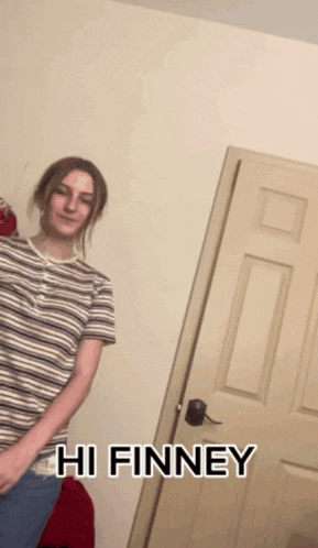 a woman in a striped shirt is standing in front of a door with the words hi finney on it