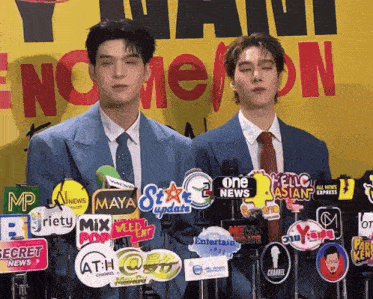 two men standing in front of microphones with logos for one news and maya