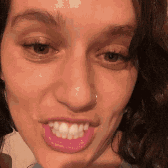 a close up of a woman 's face with a nose ring and red lips