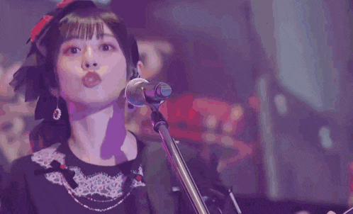 a woman singing into a microphone while playing a guitar
